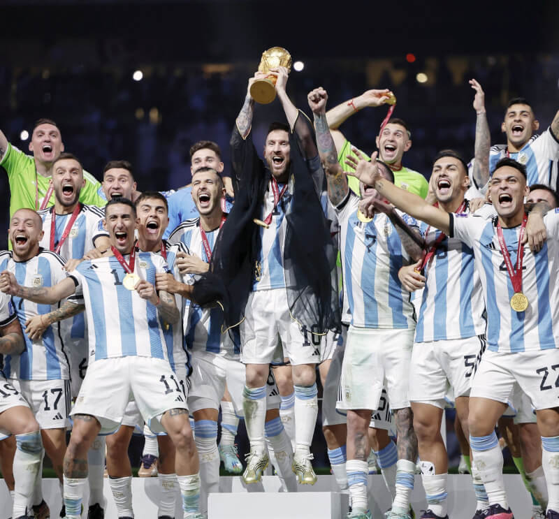 阿根廷18日在卡達世界盃決賽擊敗衛冕軍法國，勇奪隊史第3冠，梅西（中）手捧冠軍金盃歡呼。（共同社）