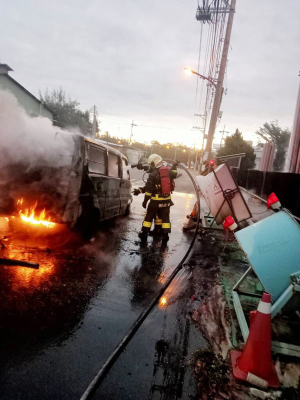 苗栗縣竹南鎮仁愛路19日發生火燒車意外，一輛停放在光電廠旁的廂型車突然起火燃燒，消防隊員趕抵現場，立刻拉出水線灌救將火勢撲滅，無人傷亡。（民眾提供）中央社記者管瑞平傳真  111年12月19日