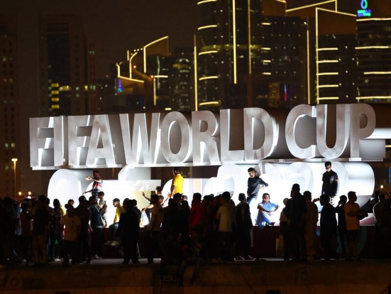 卡達民眾11月在杜哈一處世界盃足球賽看板面前合影留念。（路透社）