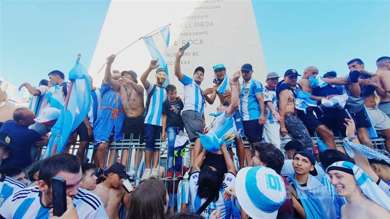 18日卡達世界盃冠軍戰阿根廷擊敗法國後，阿根廷首都布宜諾斯艾利斯景點方尖碑湧入超過百萬民眾，齊聚歡慶，民眾爬上方尖碑的圍牆，慶祝梅西為大家帶回36年來的第3座冠軍獎盃。中央社記者黃韻如布宜諾斯艾利斯攝 111年12月20日