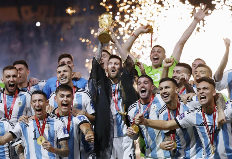 梅西（中）帶著阿根廷隊加冕第3座世界盃足球賽冠軍。（共同社）