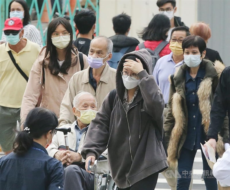 疫情指揮中心指揮官王必勝21日表示，台灣COVID-19疫情正緩步上升，估明年1月底、2月初達高峰。圖為台北市街頭民眾戴口罩過馬路。（中央社檔案照片）