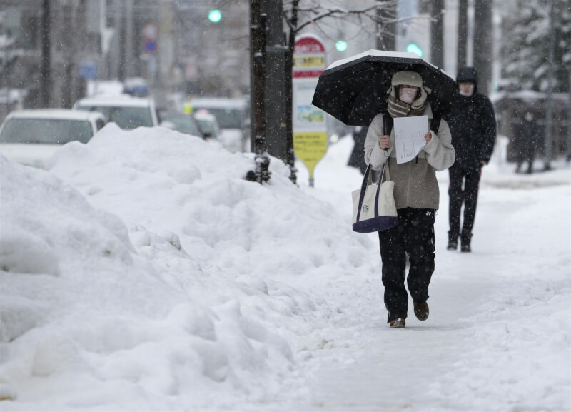 圖為去年12月23日北海道札幌市民眾在大雪中行走。（共同社）