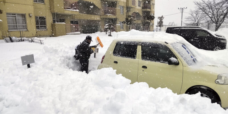 北海道札幌24日下雪，民眾在停車場清理積雪。（共同社）