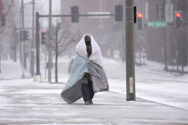 美國聖路易斯22日下雪，民眾裹著毯子外出。（美聯社）