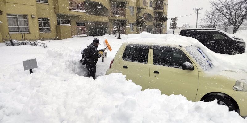 寒流襲日本，北海道北見市的民眾24日清掃車子附近的積雪。（共同社）