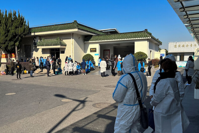 上海市正邁入COVID-19首波感染高峰，圖為上海民眾做好個人防護前往殯儀館。（路透社）