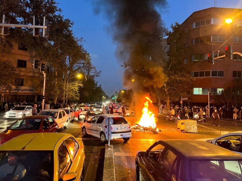 伊朗女子艾米尼9月遭警察羈押後死亡，引發全國示威，民眾9月19日在首都德黑蘭街頭抗議，一輛警用摩托車起火燃燒。（West Asia News Agency via 路透社）
