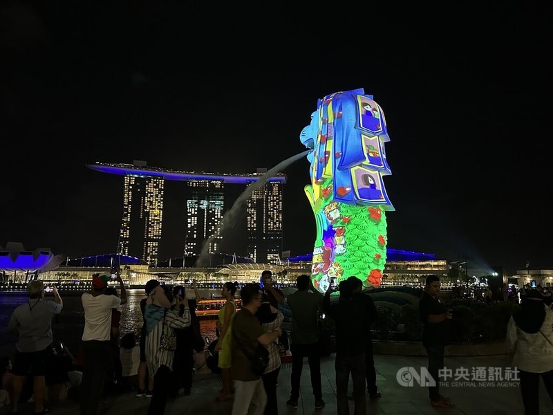 新加坡濱海灣跨年倒數活動之一包括26日至31日登場的投影秀，魚尾獅外觀變身畫布，展示學生創作的藝術作品，訴說民眾行善小故事，十分吸睛。圖攝於26日。中央社記者侯姿瑩新加坡攝  111年12月27日