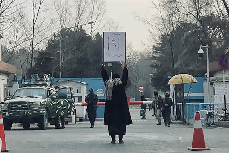 阿富汗女學生馬瓦25日隻身前往喀布爾大學，在門口高舉「要讀書」海報抗議。（法新社）