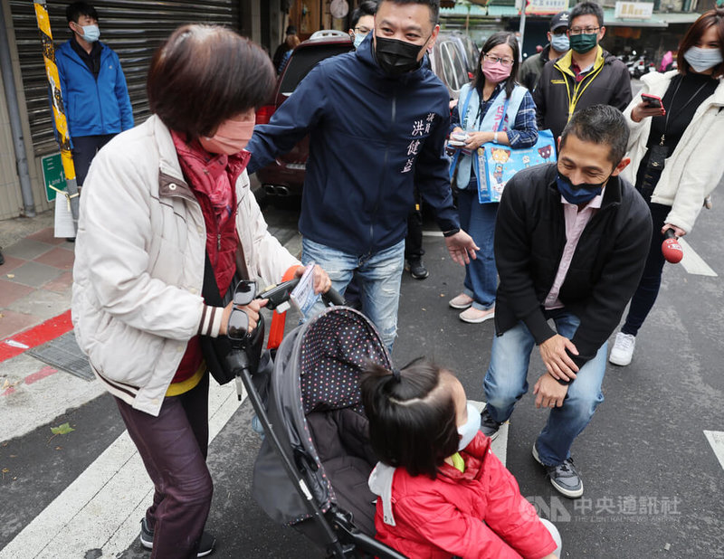 民進黨台北市第3選區立委補選候選人吳怡農（前右）28日前往撫遠街傳統市場拜票，向民眾請託支持。圖為吳怡農蹲下來和小朋友微笑致意。中央社記者王飛華攝  111年12月28日