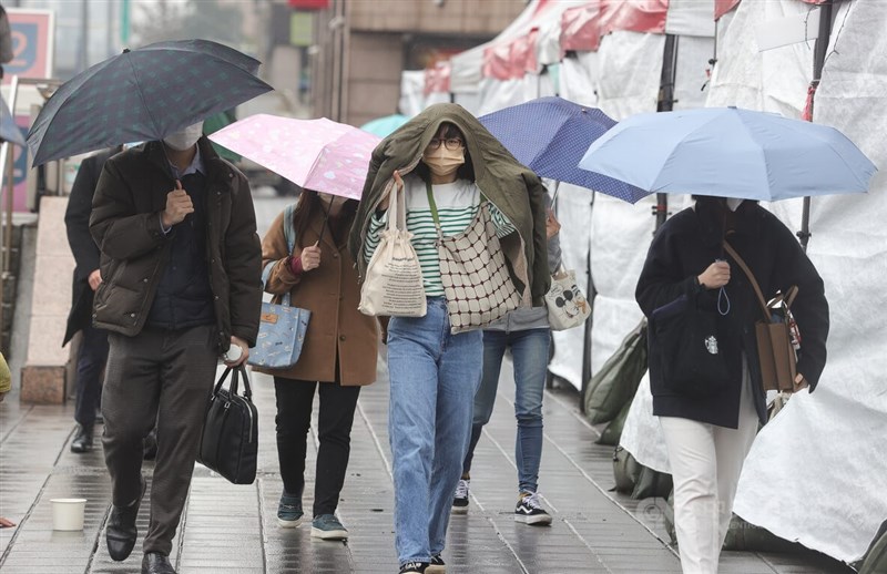 29日新增2萬7803例COVID-19本土病例。圖為台北市中正區街頭民眾用外套擋雨。中央社記者謝佳璋攝 111年12月29日