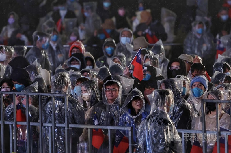 民國112年元旦升旗典禮1日在總統府前舉行，民眾穿雨衣、帶著國旗前來，一同迎接新年。中央社記者趙世勳攝 112年1月1日