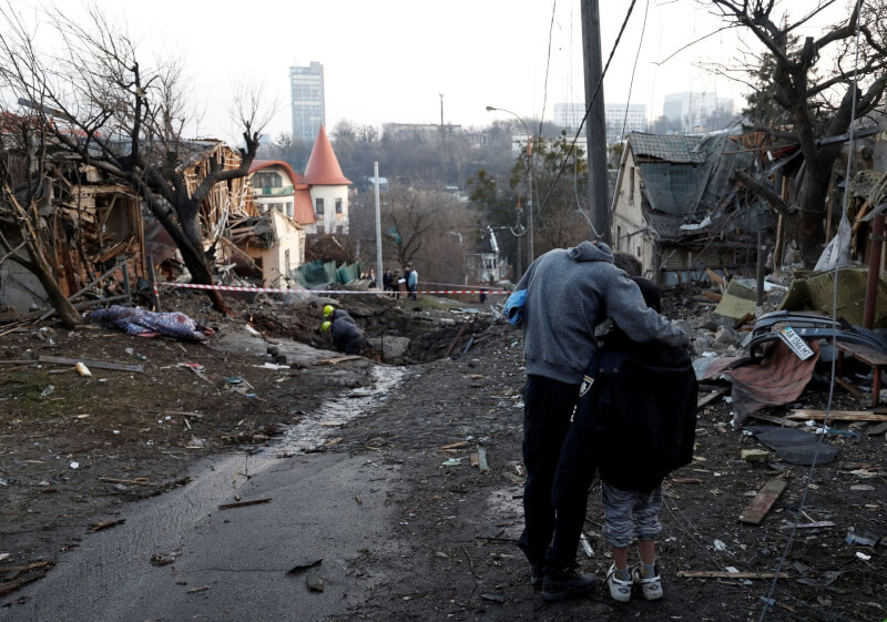 圖為12月31日基輔遭俄羅斯轟炸，一位市民在滿目瘡痍街上擁抱兒子。（路透社）