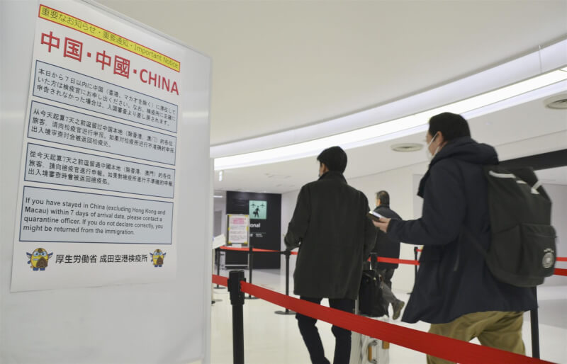 圖為去年12月30日，成田機場自中國入境旅客排隊篩檢。（共同社）