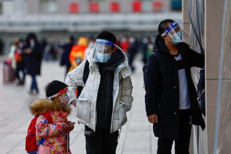 圖為7日中國民眾戴著防護面罩走入北京火車站。（路透社）