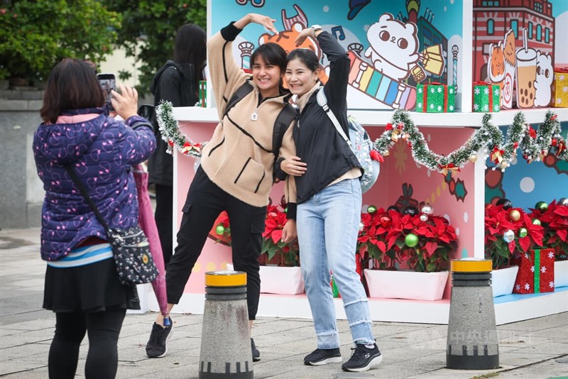 戶外應全程佩戴口罩的規定去年12月1日起取消，台北市西門町商圈遊客拿下口罩開心拍照留念。（中央社檔案照片）