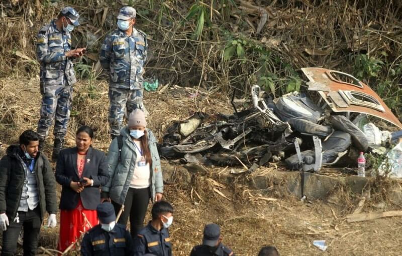 尼泊爾雪人航空客機15日墜毀，救難人員站在客機殘骸旁。（路透社）
