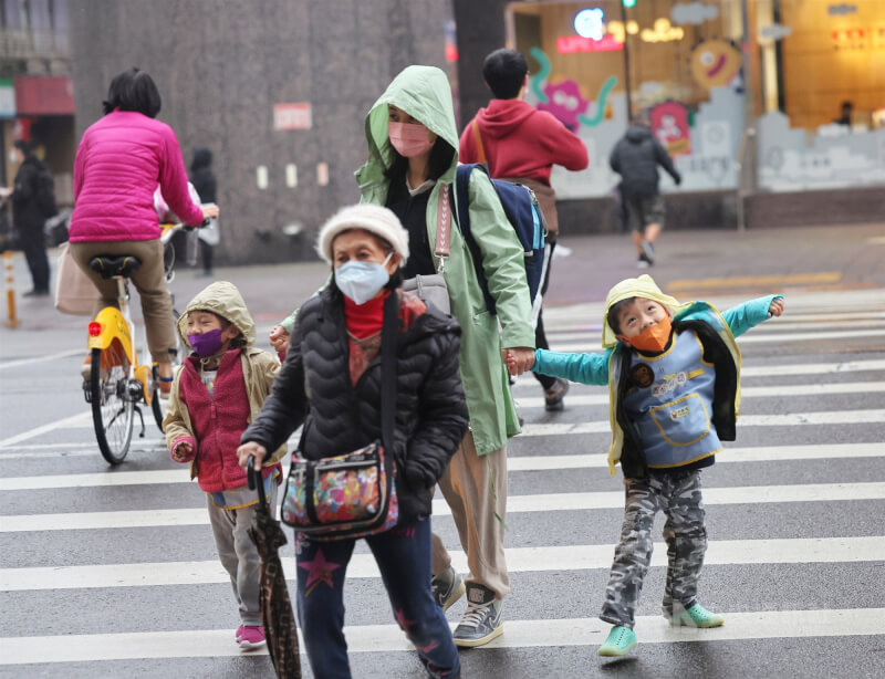 圖為台北市松山區民眾穿外套帽子保暖。（中央社檔案照片）