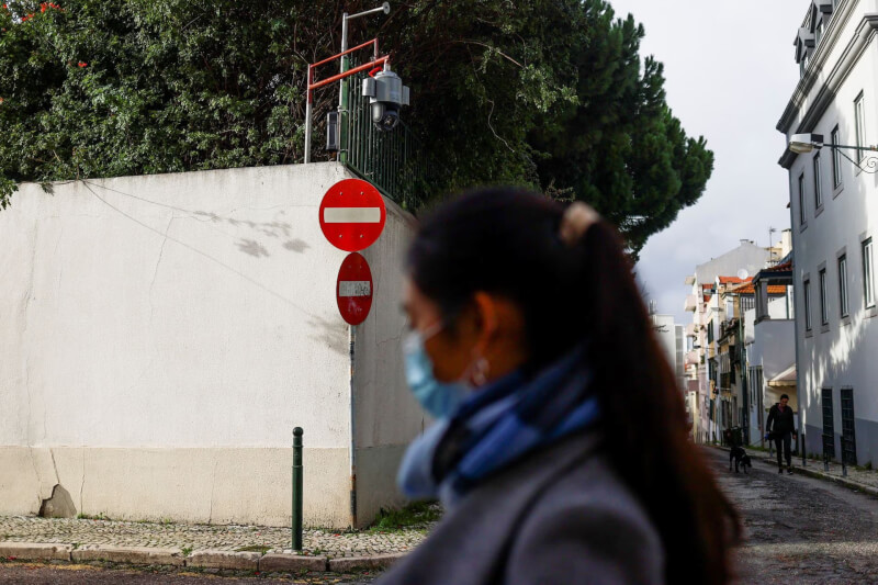 圖為去年12月21日一名婦女經過中國駐里斯本大使館外的監控攝影機。（路透社）
