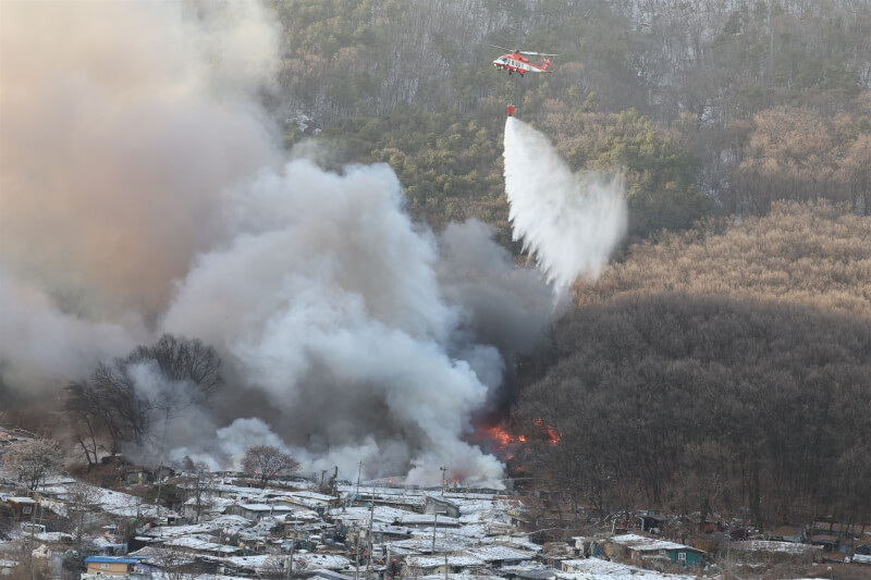 韓國首爾貧民窟九龍村20日清晨發生大火，消防單位出動直升機滅火。（韓聯社）