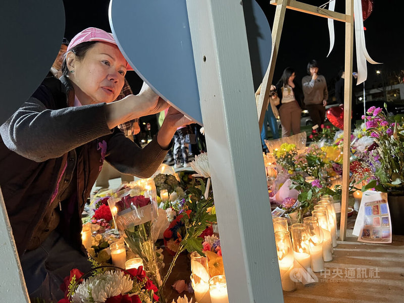 加州蒙特瑞公園市（Monterey Park）舞星大舞廳槍擊案的一名倖存者24日在寫有罹難者名字的看板寫字留言，哀悼已故友人。中央社記者林宏翰洛杉磯攝 112年1月26日