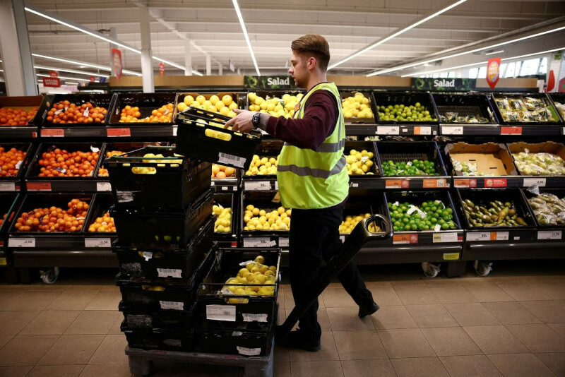 英國通膨嚴重不僅低收家戶受苦，連受薪階級都吃不消圖為超商員工補充貨架上的蔬果。（路透社）