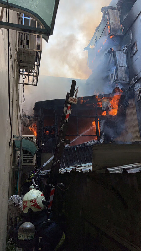 高雄市鳳山區一棟3樓加蓋鐵皮透天建築26日發生火警，火勢猛烈，消防人員到場灌救並在樓梯間發現一具焦屍，初判為屋內約90歲的獨居老翁。（高雄市消防局提供）中央社記者洪學廣傳真 112年1月26日