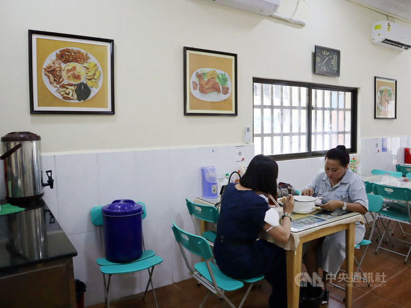 柬埔寨民眾對於台灣美食很好奇，常會到蔡昀芳的「小月小吃」嚐鮮，圖為當地消費者正在用餐，餐廳牆上掛著炸雞腿飯、滷味拼盤等台灣美食照片。中央社記者陳家倫金邊攝 112年1月28日