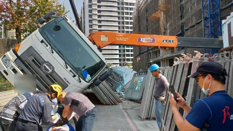 高雄市仁武區7日中午發生工安意外，一處工地在吊掛鷹架時，因拖板車外伸撐座未展開至最大位置，導致拖板車傾倒，造成車上鷹架滑落壓傷金姓、陳姓勞工。（高雄市消防局提供）中央社記者洪學廣傳真  112年2月7日