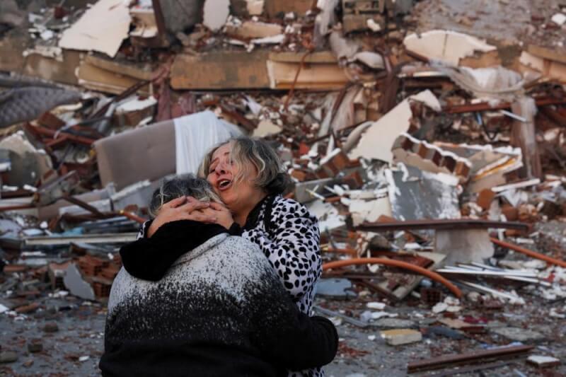 土耳其哈泰發生地震後，建築物倒塌，一名婦女7日在災區擁抱家人。（路透社）