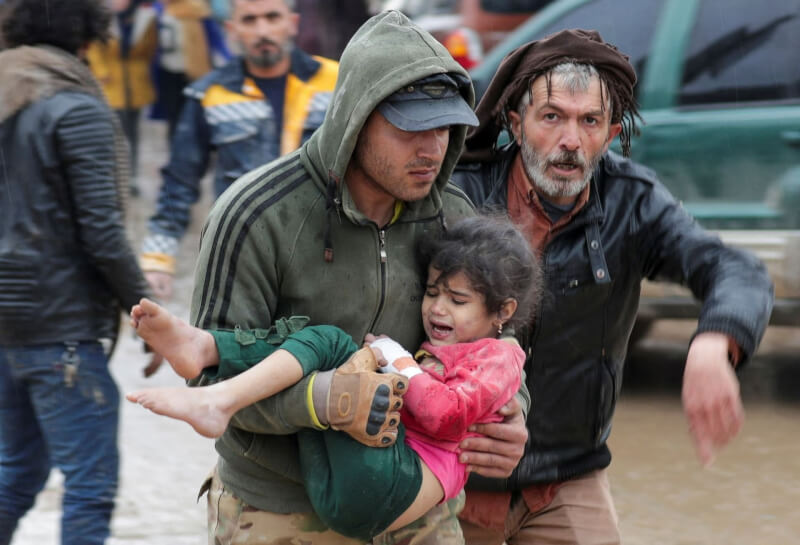 6日地震發生後，敘利亞反抗軍掌控的堅達里斯鎮一名男子抱著受驚嚇的女童。（路透社）
