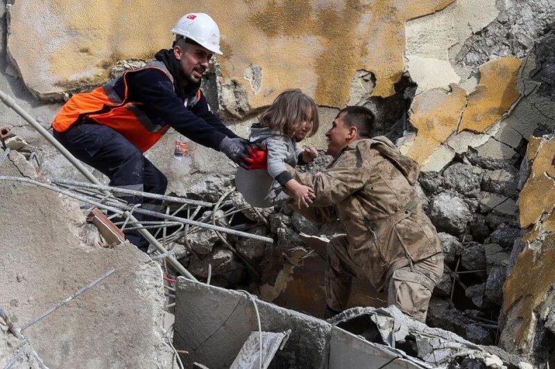 土耳其南部與敘利亞接壤地區6日發生芮氏規模7.8強震，各國馳援災區。圖為哈泰省救援人員7日將受困孩童從受損建物中抱出。（路透社）