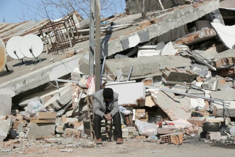 土耳其與敘利亞邊界地區6日發生規模7.8強震，死亡人數已突破2萬8000人。圖為11日土耳其阿德亞曼一名男子坐在倒塌的建築物前。（路透社）