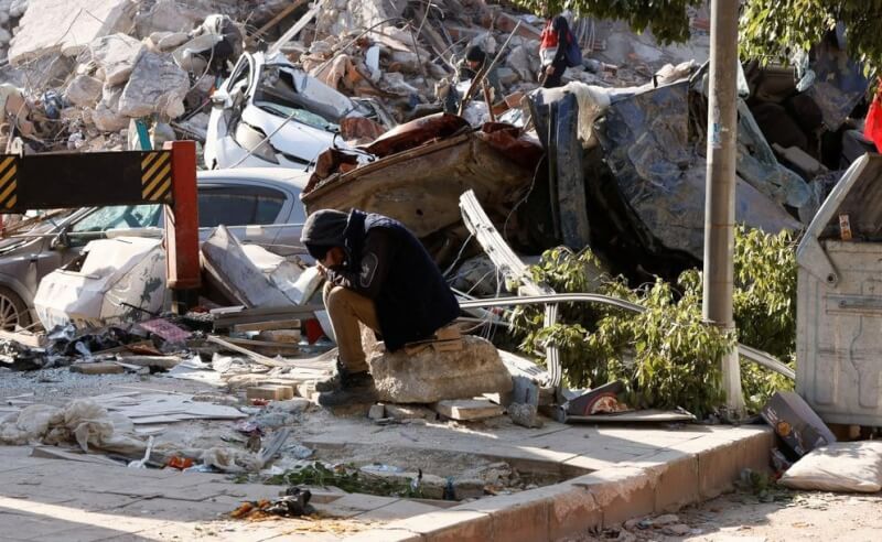 土耳其強震後，哈泰省建築物倒塌，9日災民坐在斷垣殘壁中。（路透社）