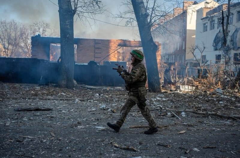 2月3日烏東巴赫姆特遭猛攻，一名烏克蘭軍人經過遭炸毀的建築物。（路透社）