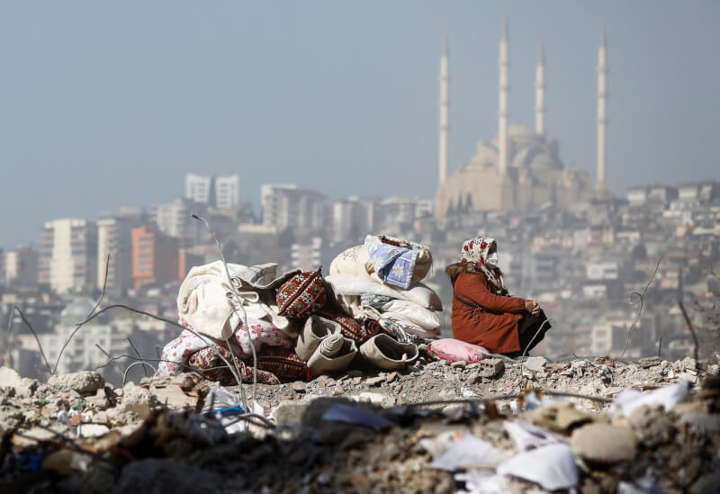圖為14日土耳其卡拉曼馬拉斯城，一名女子坐在自己房子的廢墟上。（路透社）