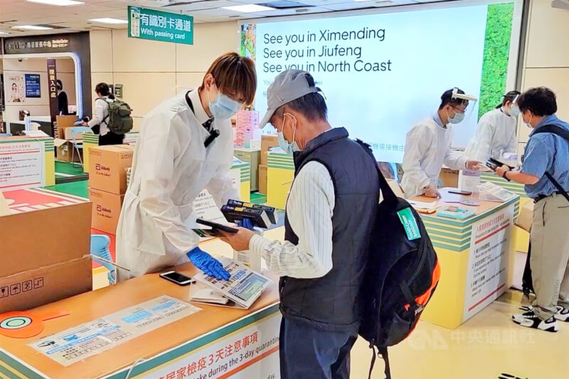 圖為去年9月桃園機場國際港埠人員向入境旅客發放快篩試劑。（中央社檔案照片）