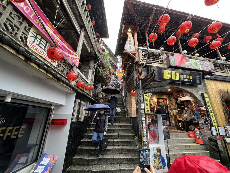 新北市瑞芳區知名景點九份25日白天天公不作美，飄下陣陣雨絲，從豎崎路石階望去，雖是假日但人潮不如以往，只見零散遊客撐傘漫步。（新北市觀光旅遊局提供）中央社記者黃旭昇新北市傳真  112年2月25日