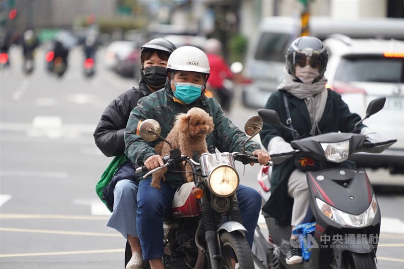 受強烈大陸冷氣團影響，中央氣象局持續發布9縣市低溫特報。圖為民眾載著愛犬騎摩托車穿梭在台北市大同區街頭。（中央社檔案照片）