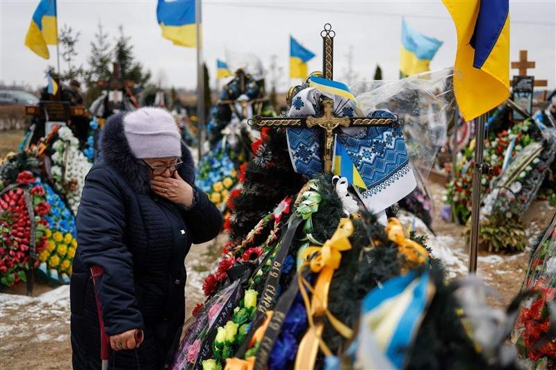 俄羅斯入侵烏克蘭屆滿一周年，基輔郊外布查鎮上一名婦人24日站在墳墓前，悼念在戰爭中死去的兒子。（路透社）