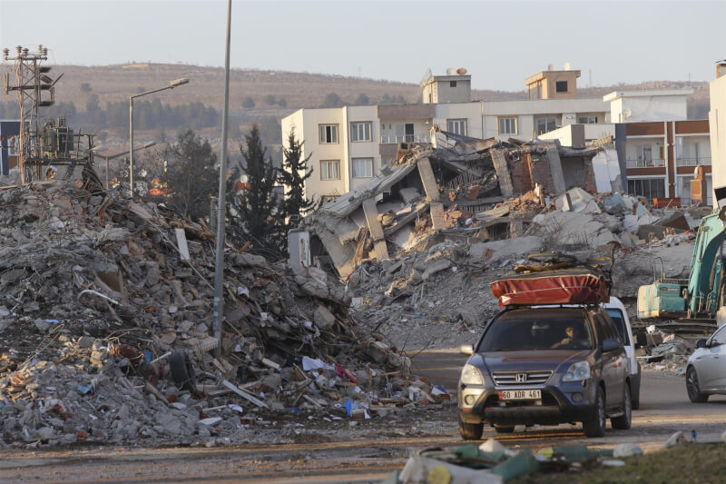 土耳其和敘利亞6日強烈地震，截至24日已逾5萬人罹難。圖為23日土耳其阿德亞曼車輛行經建物瓦礫堆附近。（共同社）