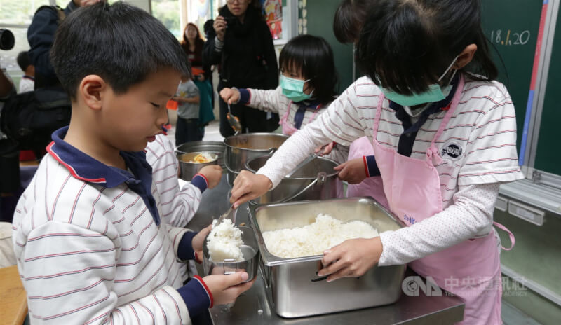 台北市多所學校112學年度將調漲營養午餐價錢。圖為台北市一間國小學童為同學打飯。（中央社檔案照片）