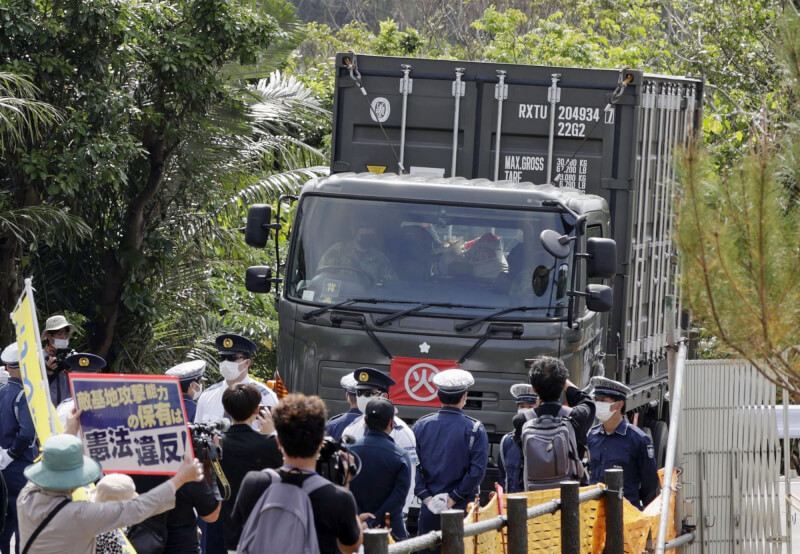 日本海上自衛隊大隅號運輸艦18日駛入石垣港，卸下約15輛載有彈藥的自衛隊車輛並開往駐屯地，反對的民眾舉標語抗議。（共同社）