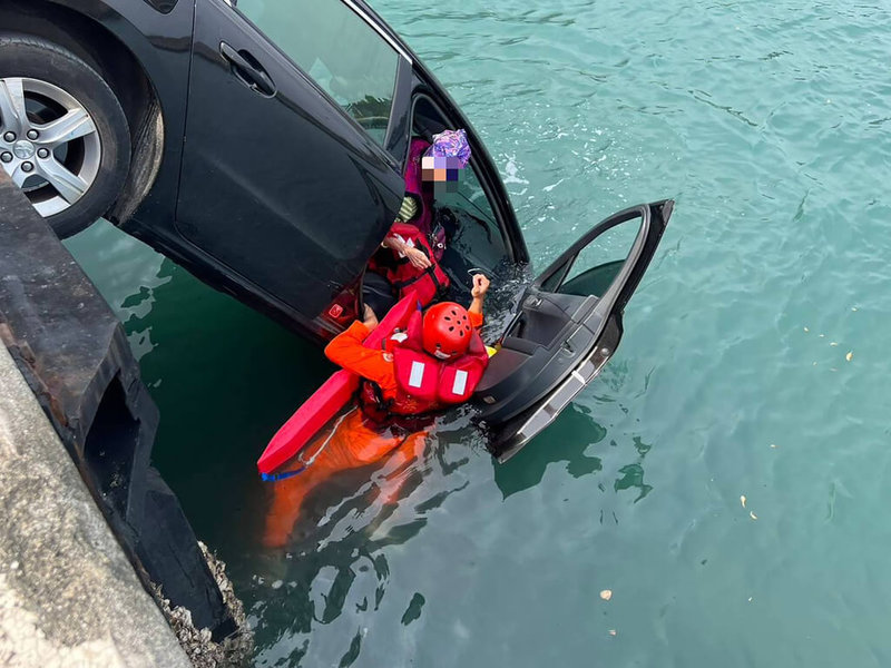 台東縣東河鄉金樽漁港21日一輛自小客車因駕駛忘記拉手煞車就下車，導致車輛滑行直接墜海，駕駛的妻子也在車內，落海受困，所幸海巡人員及時救起。（海巡署東部分署第一三岸巡隊提供）中央社記者李先鳳傳真  112年3月21日