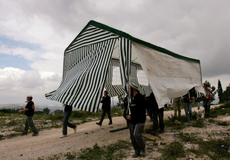 圖為2007年3月27日，以色列激進分子在約旦河西岸北部扛著一個帳篷。（路透社）