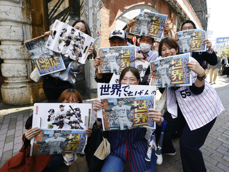 日本隊22日在世界棒球經典賽擊敗美國隊奪隊史第3冠，多家報社等在街頭贈送號外，東京民眾搶拿後，開心合影。（共同社）