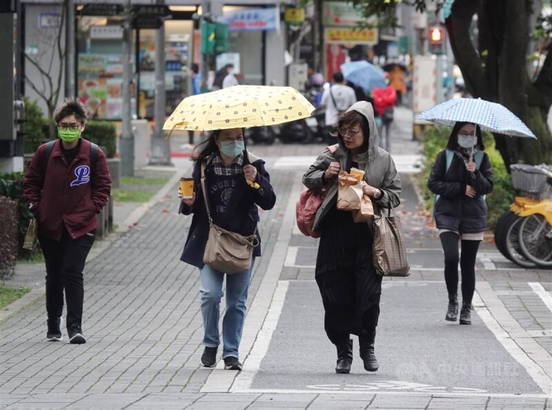 圖為26日北市南港區街頭民眾撐傘、戴帽遮雨。（中央社檔案照片）