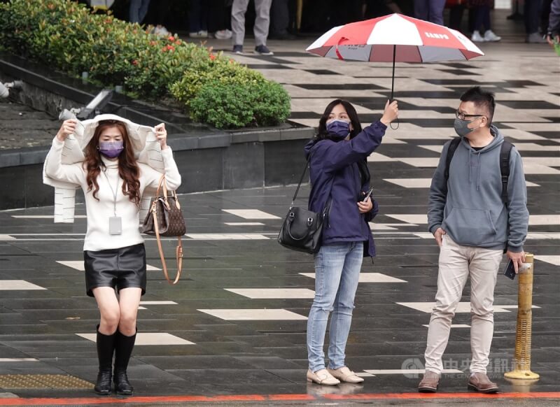 圖為台北市南港區民眾用衣服遮雨。（中央社檔案照片）
