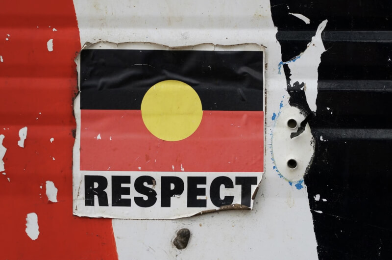 圖為澳洲原住民旗幟與寫有「尊重」字樣的貼紙。（路透社）